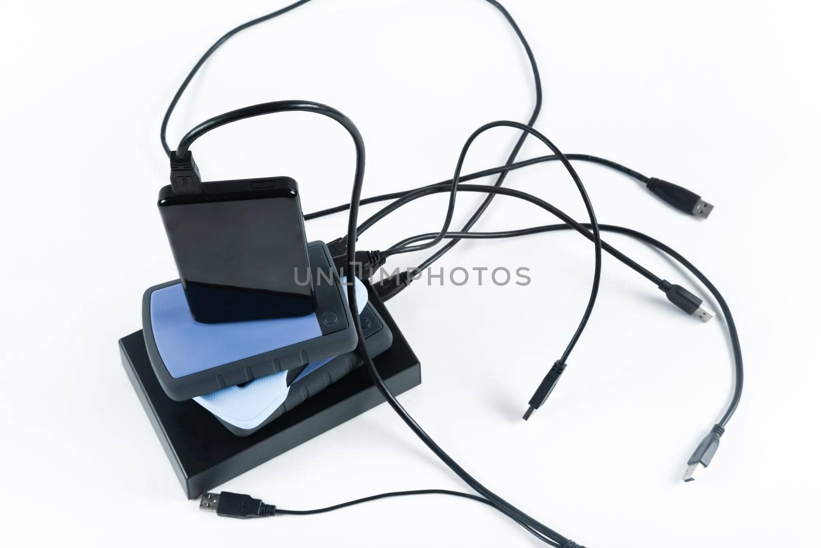 many external hard drives with wires lie on a white background. Hard drives on isolate