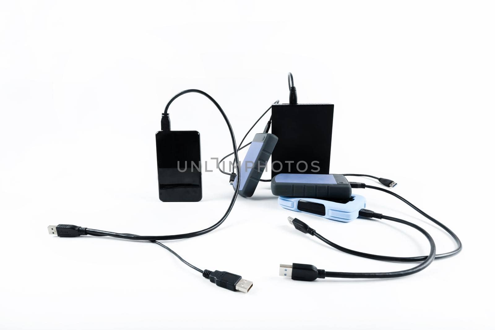 many external hard drives with wires lie on a white background. Hard drives on isolate