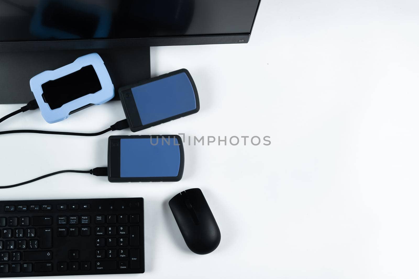 Multiple external hard drives connected to a monoblock on a white background.Computer with hard drive by Lobachad