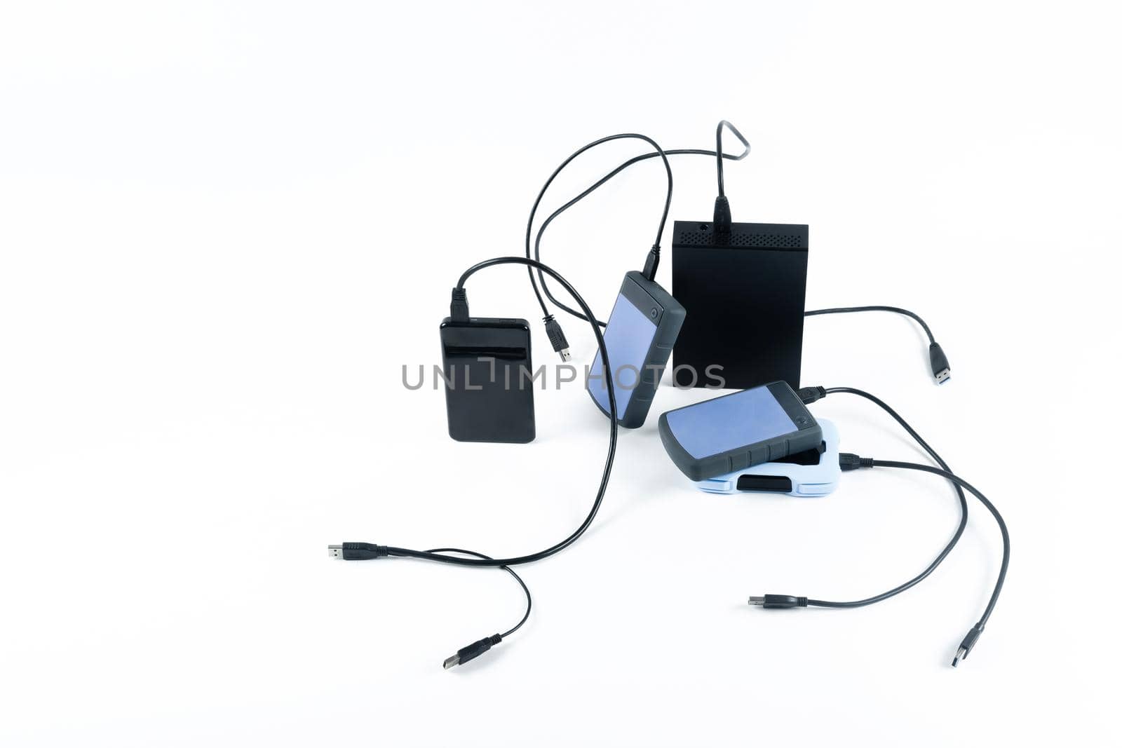 many external hard drives with wires lie on a white background. Hard drives on isolate. by Lobachad