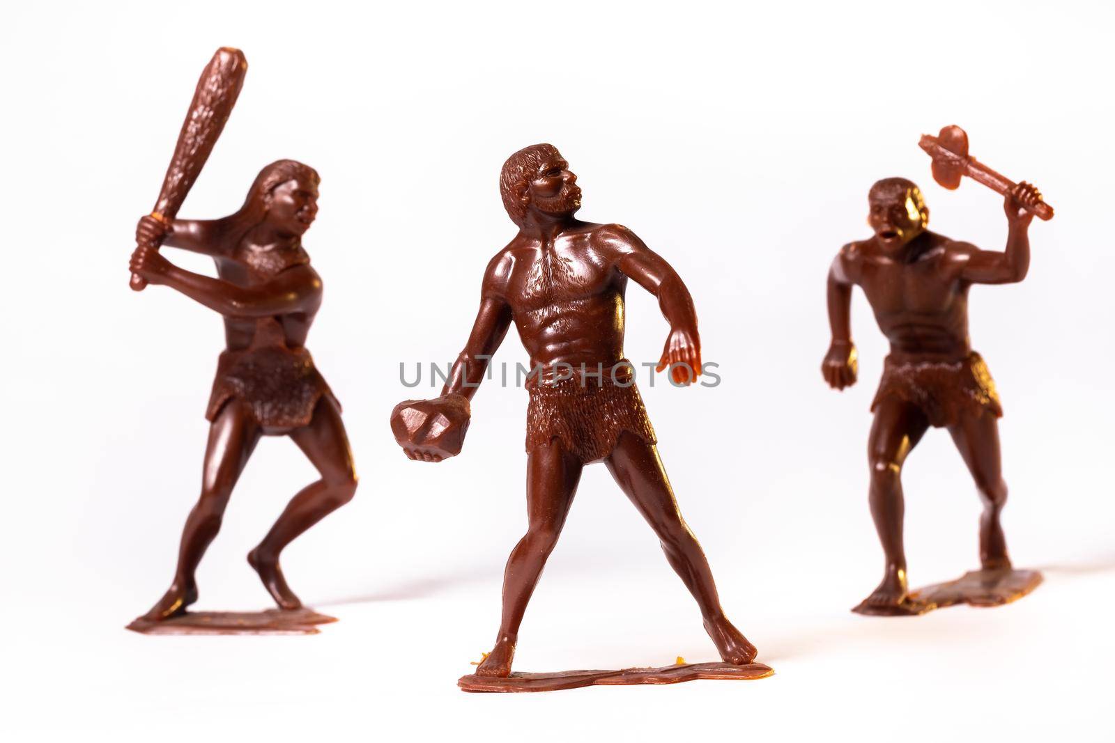 Large toy figures of primitive people on a white background.