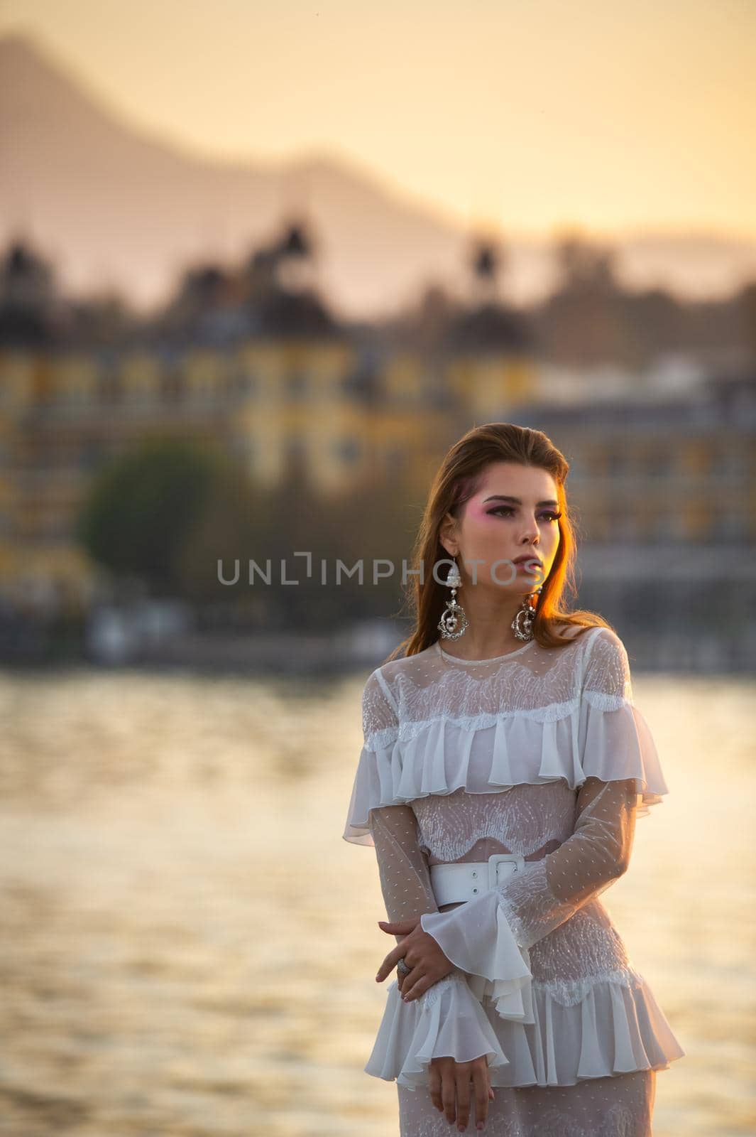 A bride in a white wedding dress in the old town of Austria at sunset by Lobachad