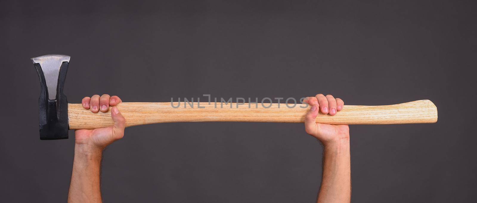 a large axe in the hands of men. a wood chopper. banner on a gray background. horizontal. copy space