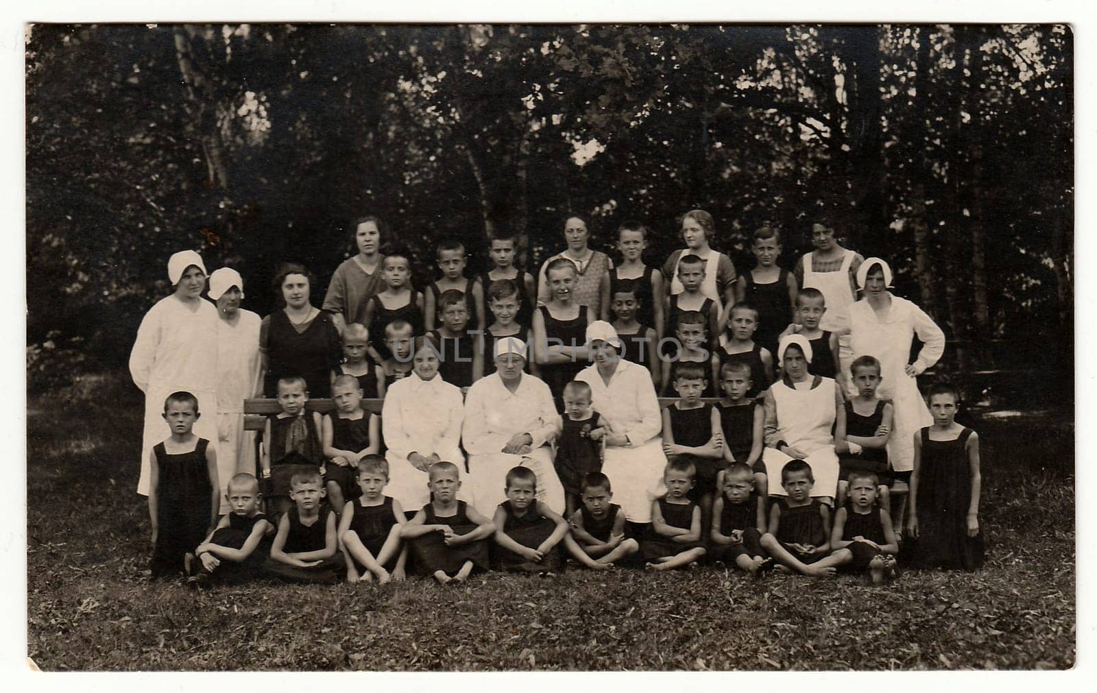 Vintage photo shows a group of boys and nurses in nature. Photo was taken in sanatorium, circa 1940s. by roman_nerud
