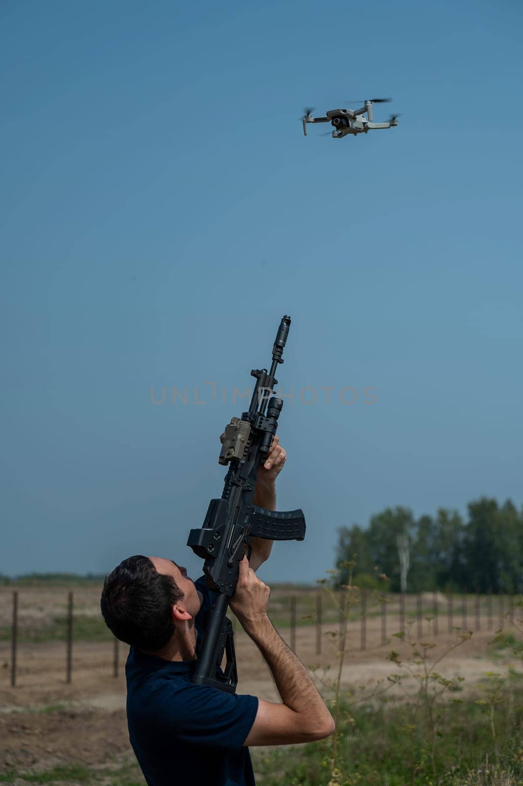 Man aiming to shoot a rifle at a flying drone outdoors. by mrwed54