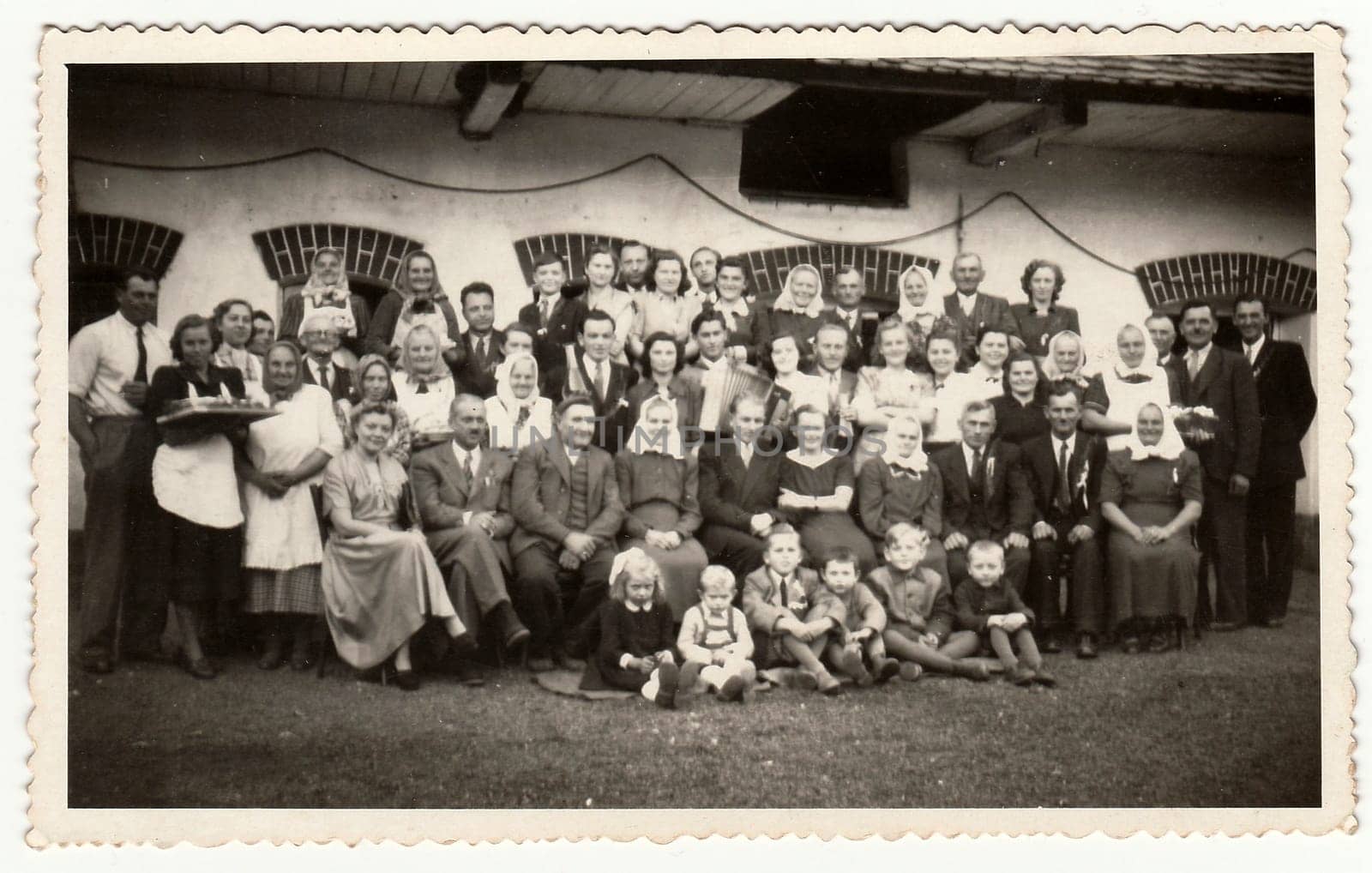 A vintage photo shows people in the back yard (during rural feast), circa 1960. by roman_nerud