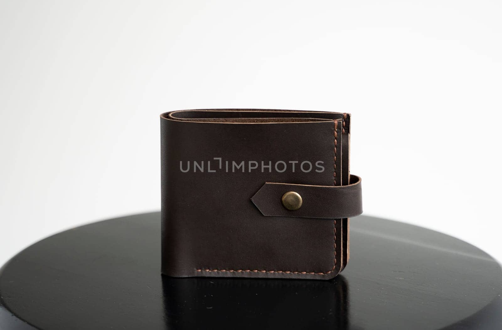 Brown genuine leather wallet on a wooden black chair with white background. Men's accessories