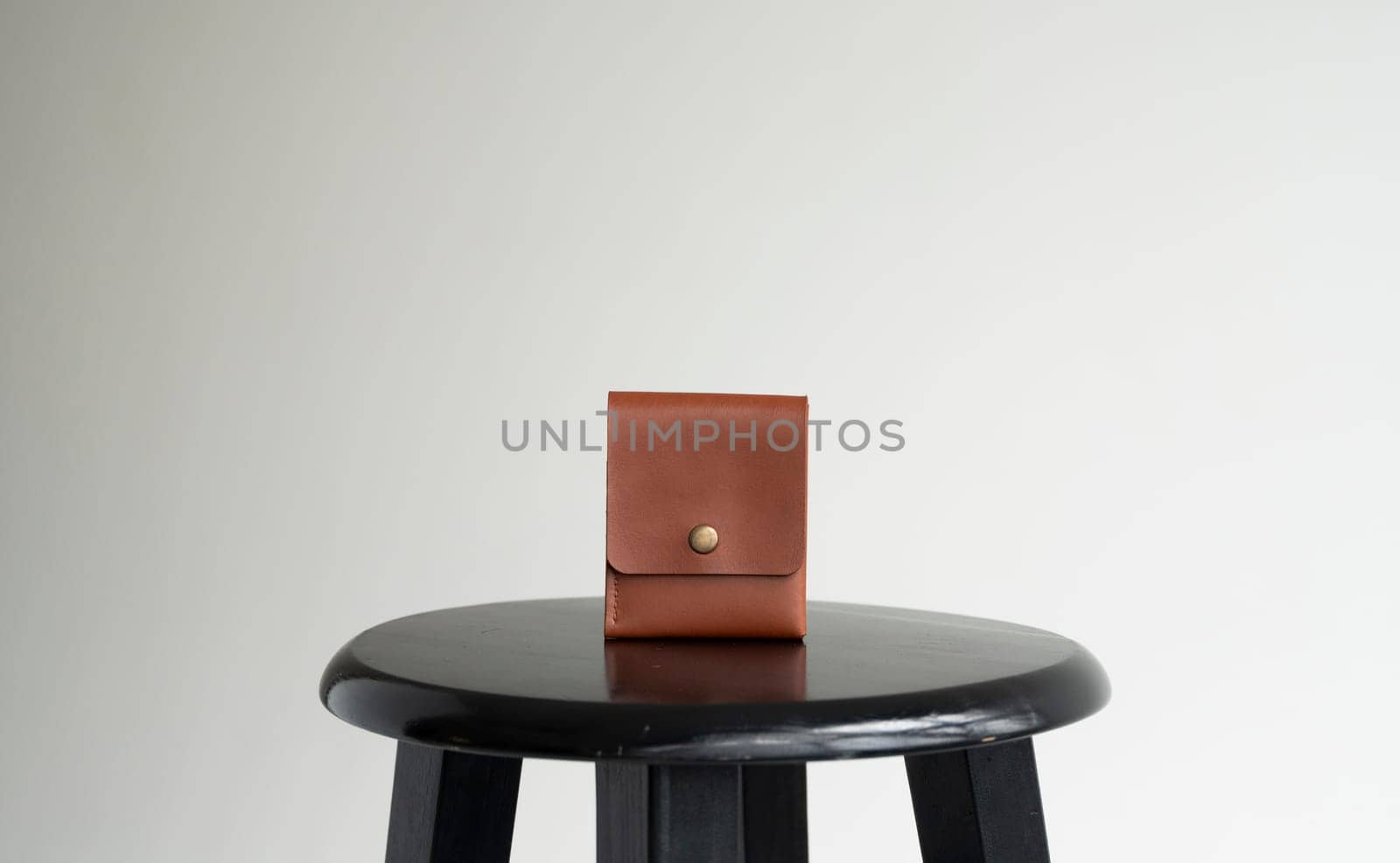 Orange men's business leather card holder on a black chair with a white background. Men's accessories