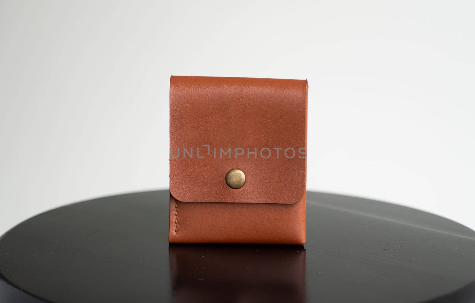 Close up orange men's business leather card holder on a black chair with a white background. Men's accessories