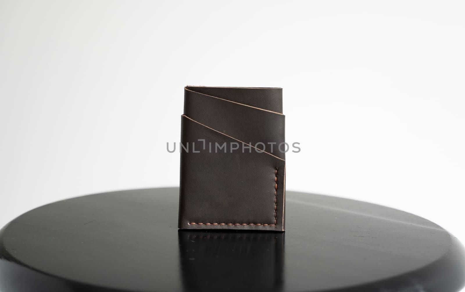 Brown men's business leather card holder on a black chair with a white background. Men's accessories
