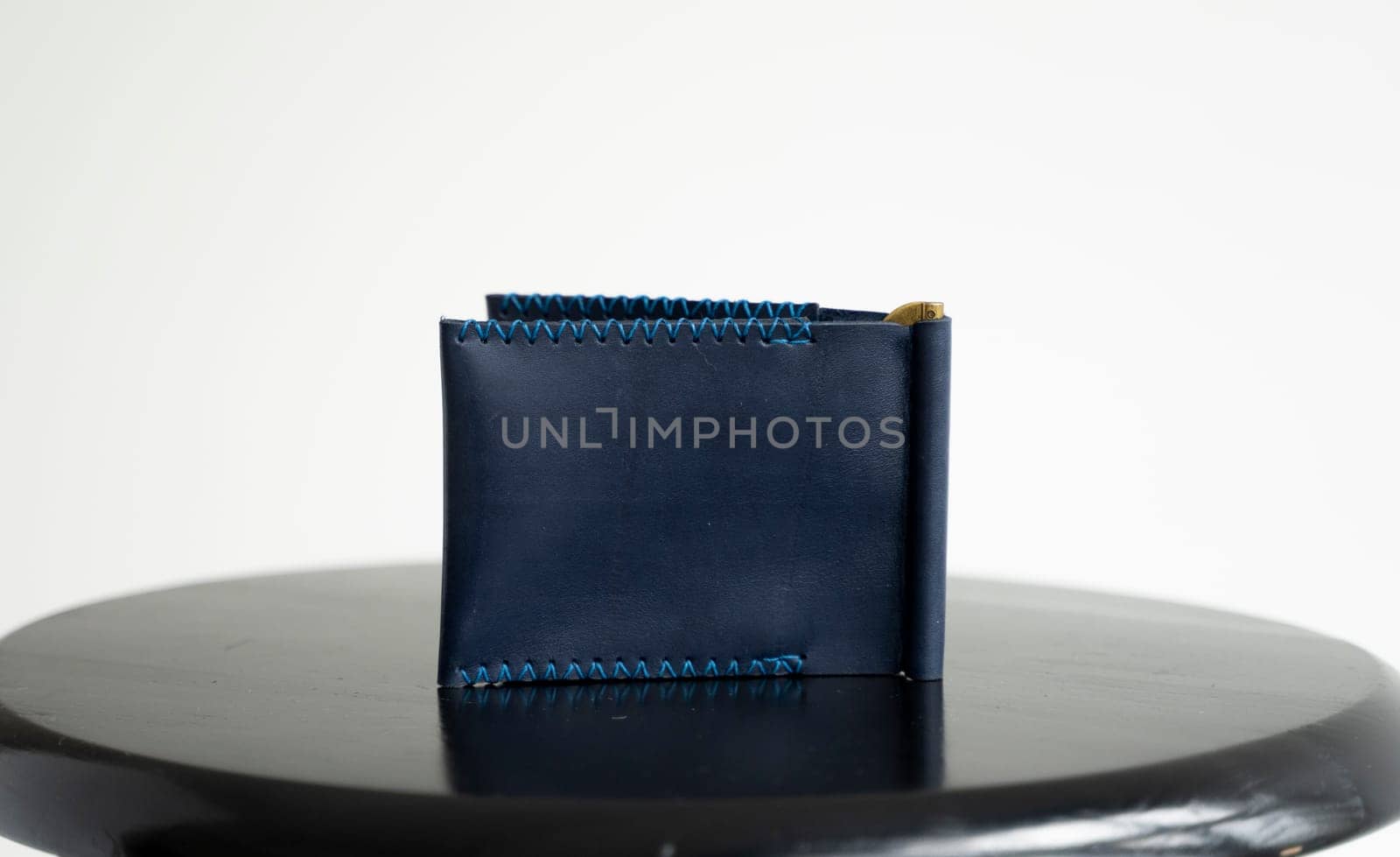 Empty blue men's money clip handmade leather wallet with a two pockets on a black table. Selective focus, copy space, Close up