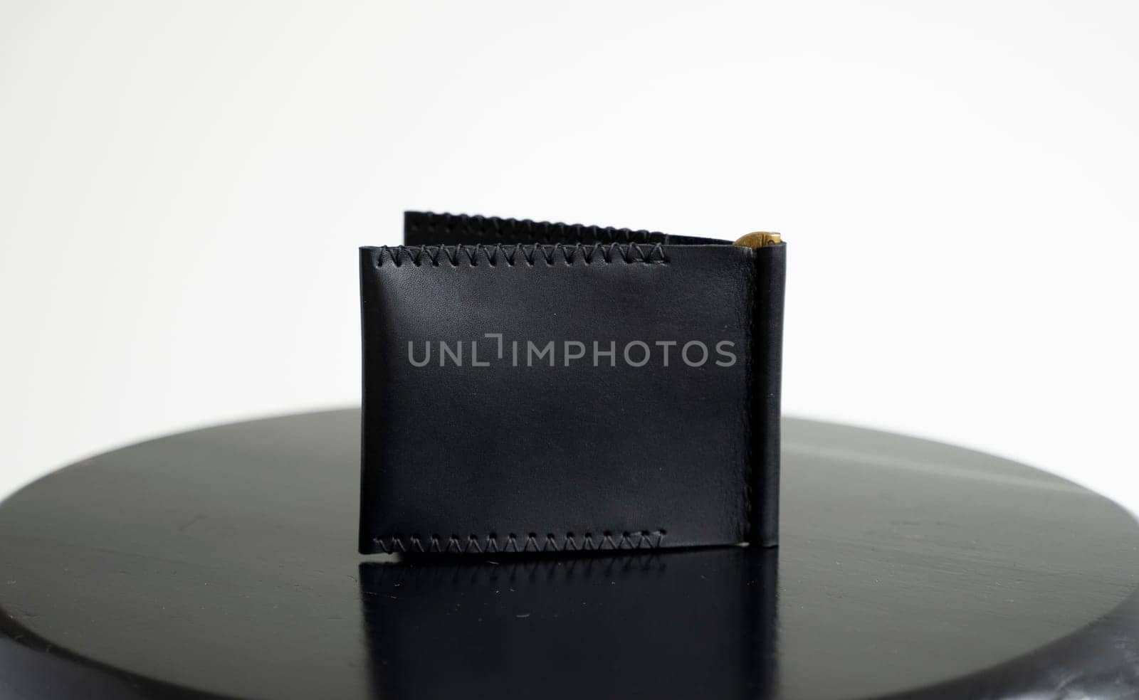 Black men's money clip handmade leather wallet with a two pockets on a black table