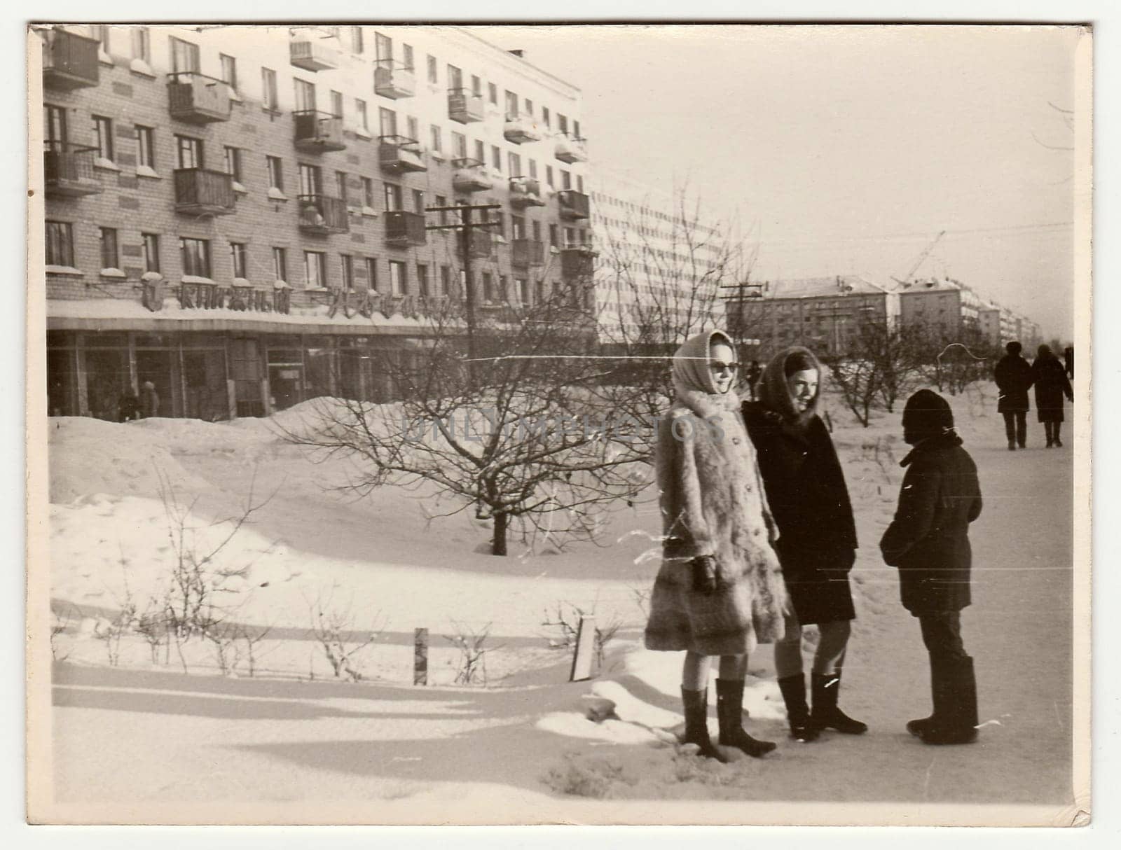 Vintage photo shows girls and boy talk on street in winter. by roman_nerud