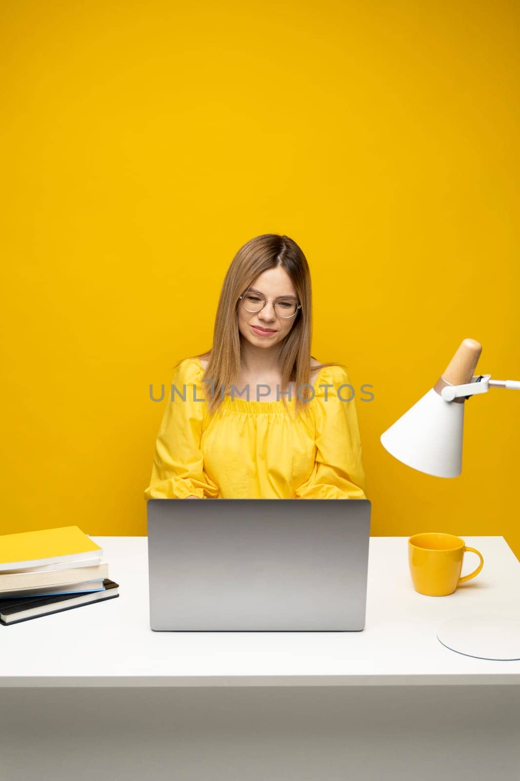 Happy millennial businesswoman negotiating with client by email messenger. Smiling young woman fashion designer sit at modern office desk use laptop at workplace