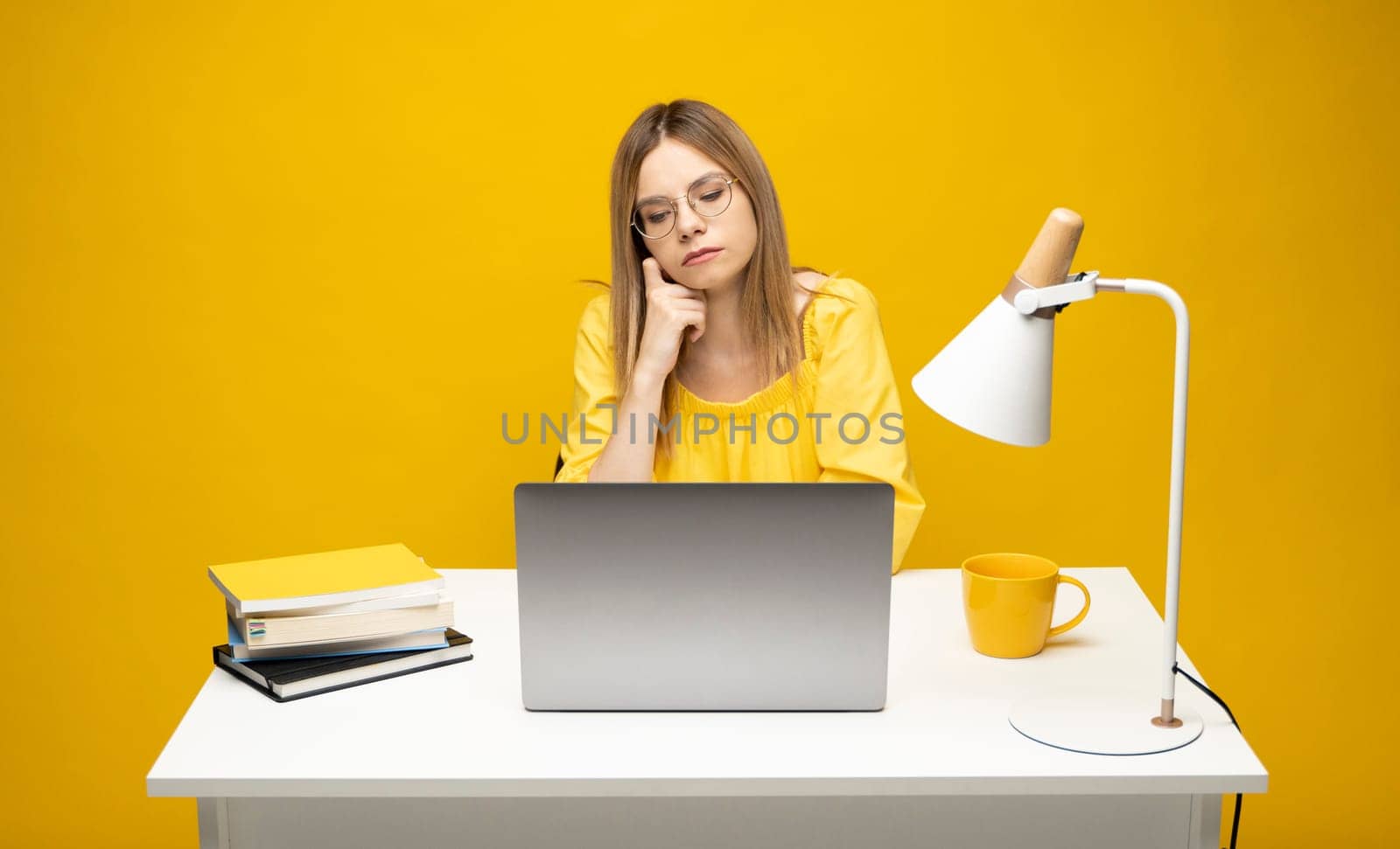 Studio portrait of young successful secretary employee business woman wear yellow t-t-shirt sit work at white office desk with laptop browsing internet online isolated on yellow background. by vovsht