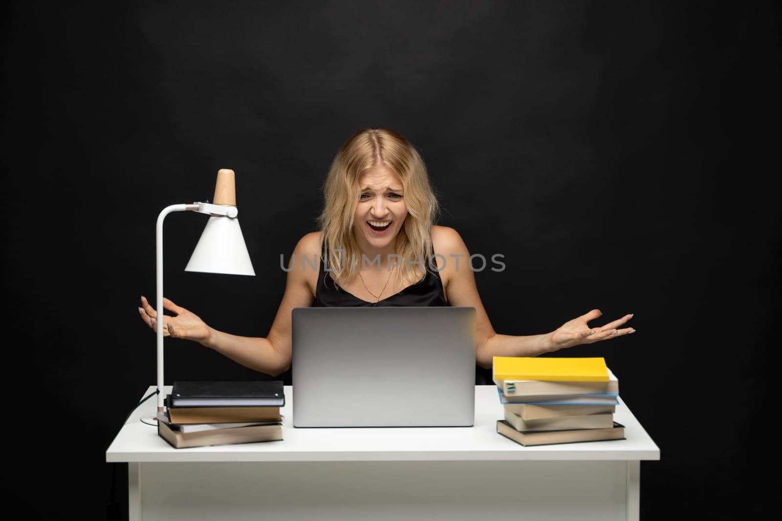 Confused blonde business woman working on a laptop on a white background