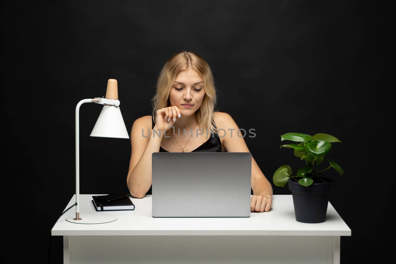 Portrait of a pretty young woman studying while sitting at the table with grey laptop computer, notebook. Smiling business woman working with a laptop isolated on a grey background