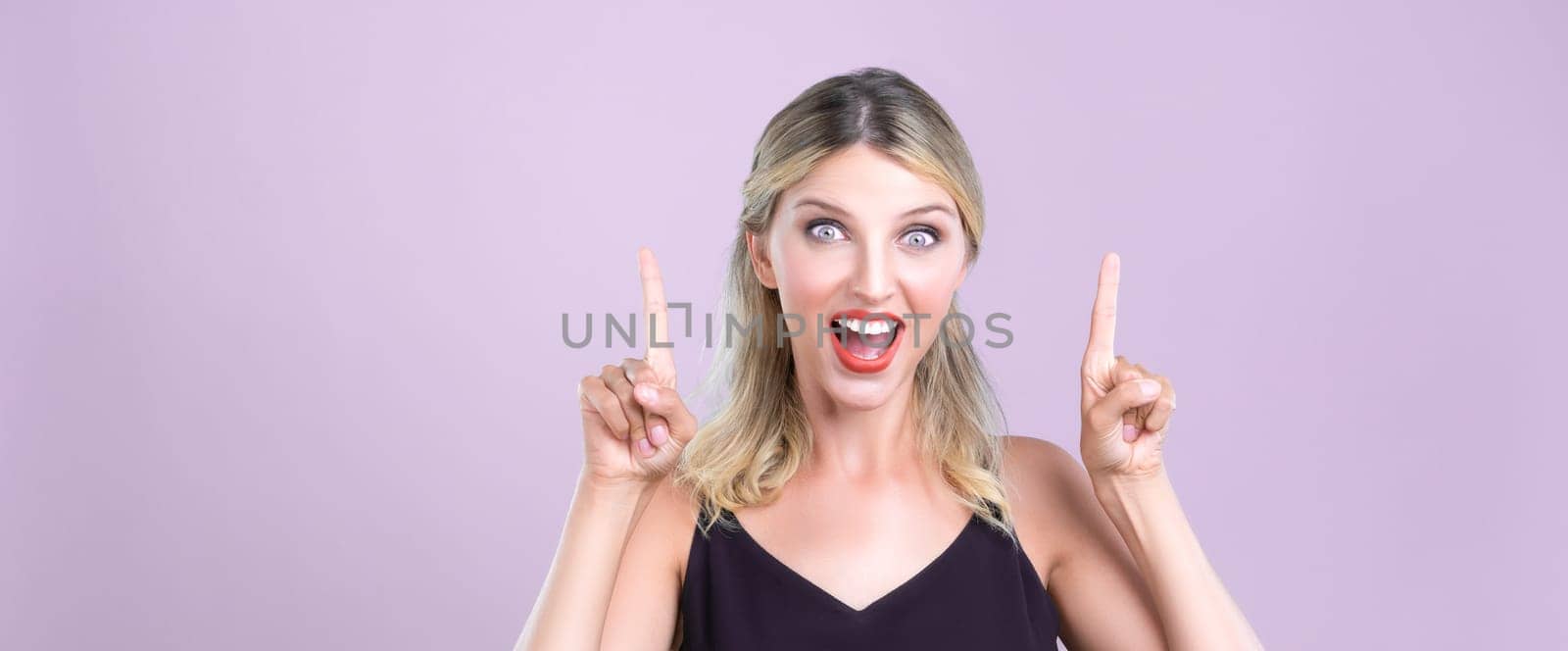 Alluring portrait of beautiful woman with perfect makeup clean skin pointing finger up in pink copyspace isolated background. Promotion indicated by hand gesture concept for skincare advertisement.