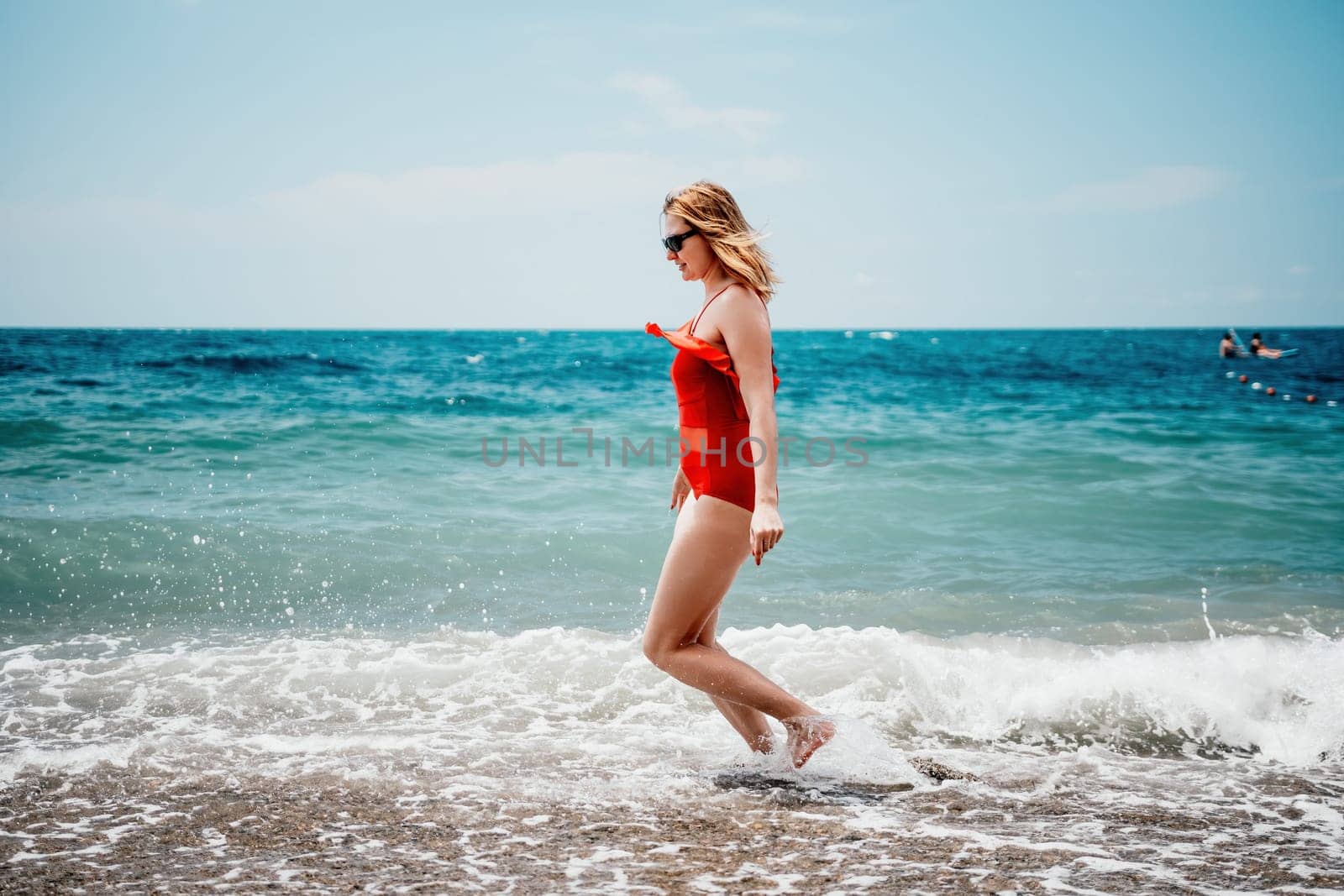 Pretty young blonde woman walking on the beach in summer, having fun, walks carefree on the seaside . Portrait beautiful young woman relax smile around beach sea ocean in holiday vacation travel trip.