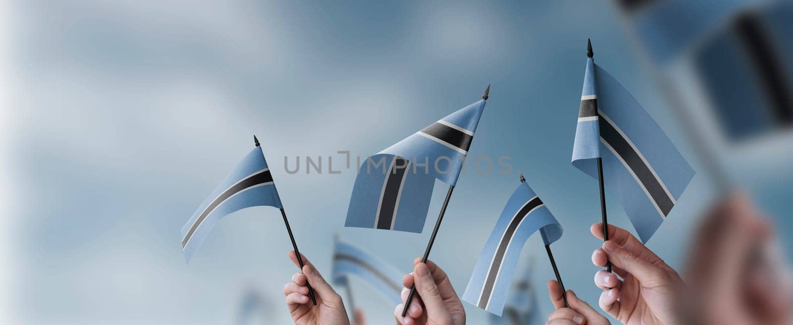 A group of people holding small flags of the Botswana in their hands.