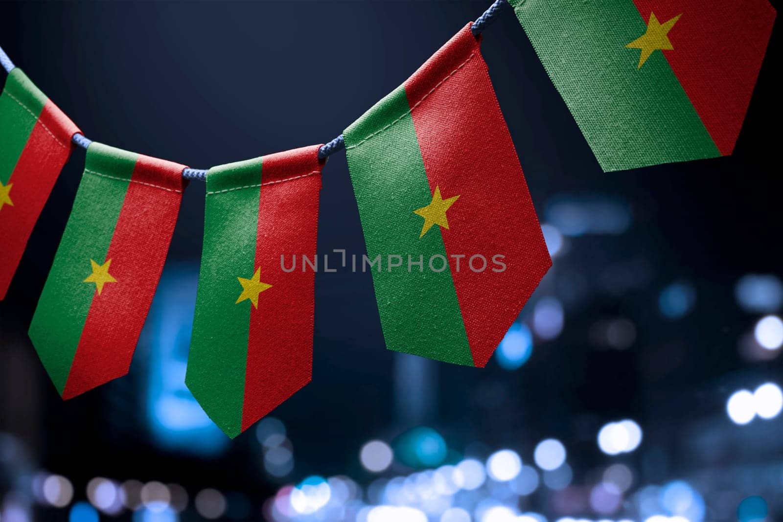 A garland of Burkina Faso national flags on an abstract blurred background.