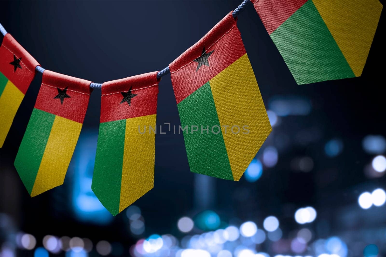 A garland of Guinea Bissau national flags on an abstract blurred background.