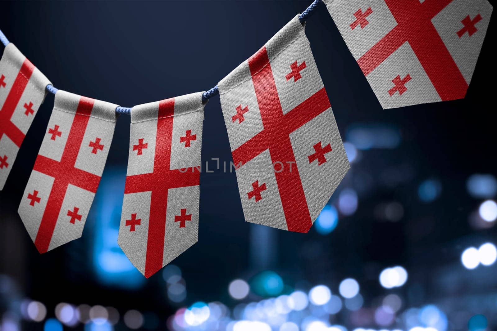 A garland of Georgia national flags on an abstract blurred background.
