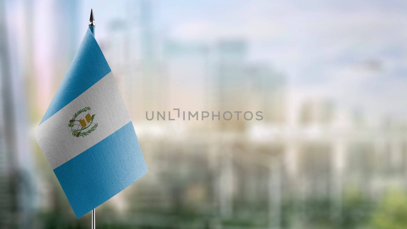 Small flags of the Guatemala on an abstract blurry background.