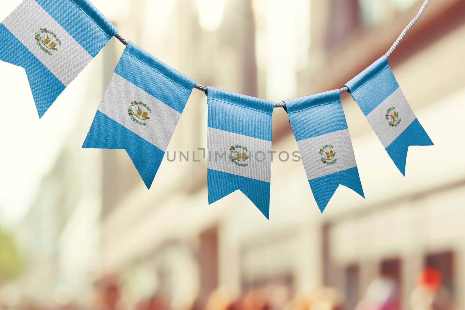A garland of Guatemala national flags on an abstract blurred background.