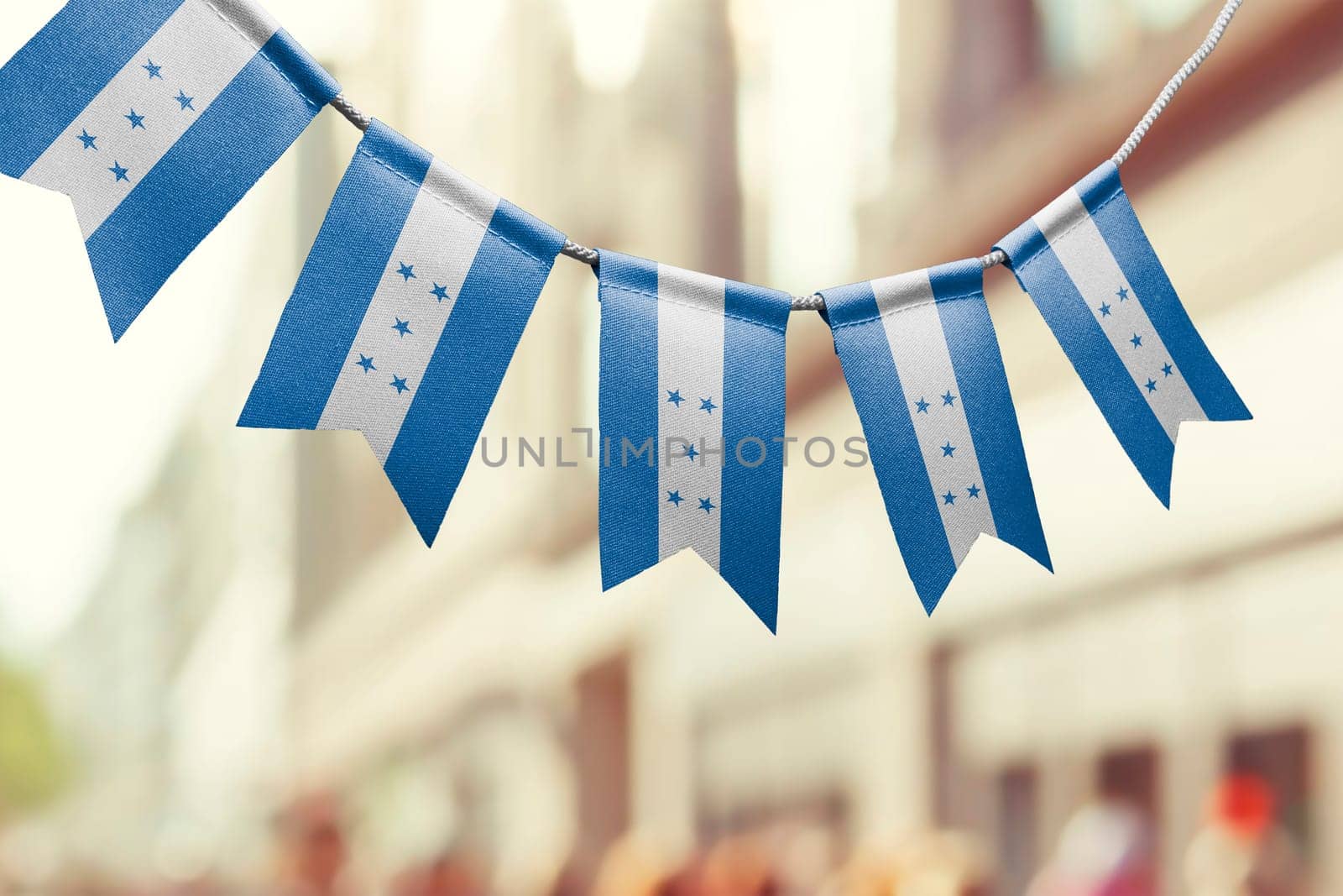 A garland of Honduras national flags on an abstract blurred background.