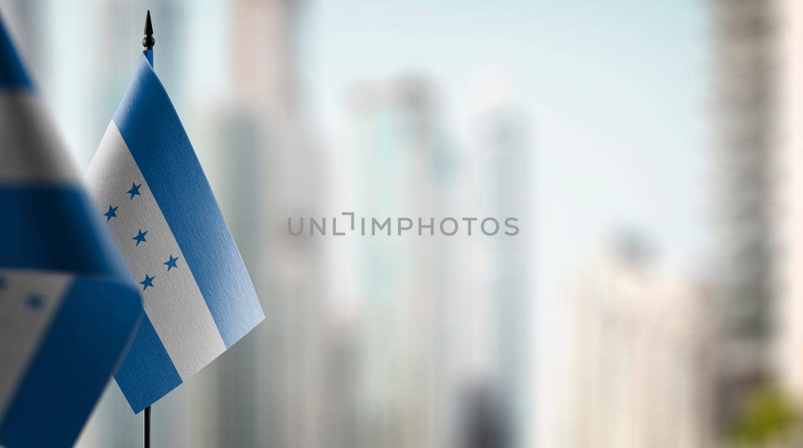 Small flags of the Honduras on an abstract blurry background.