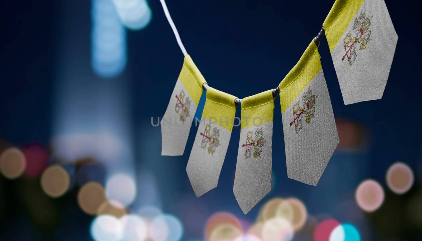 A garland of Vatican national flags on an abstract blurred background.