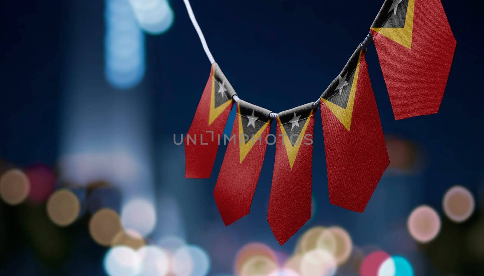 A garland of East Timor national flags on an abstract blurred background.