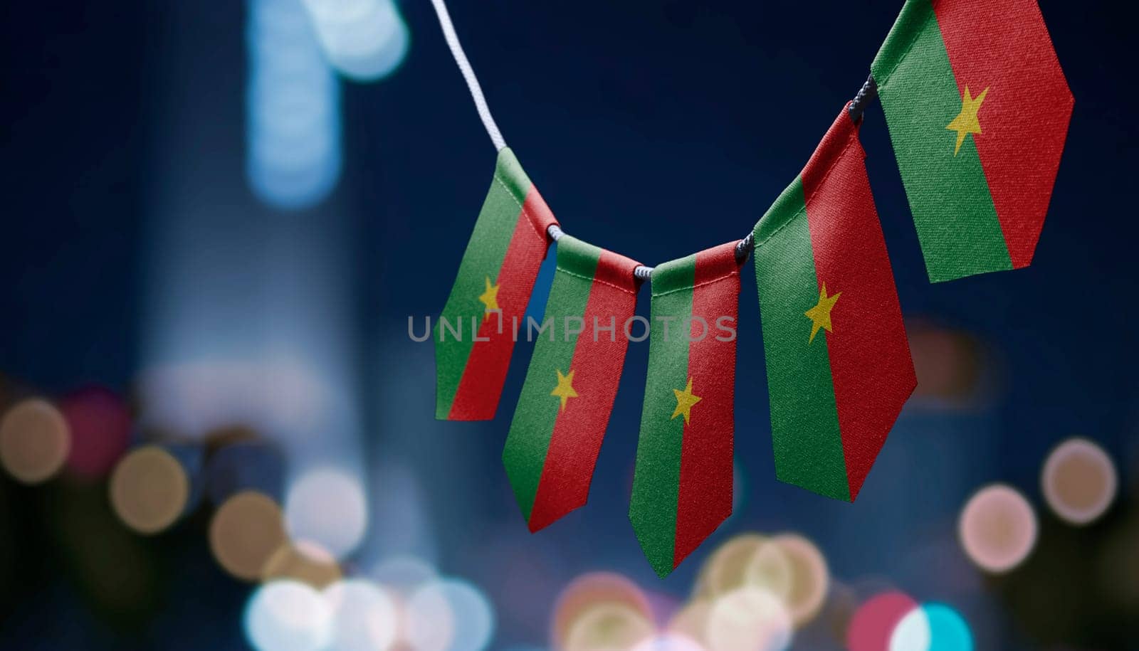 A garland of Burkina Faso national flags on an abstract blurred background.