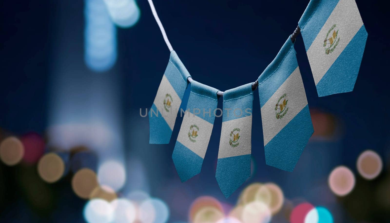 A garland of Guatemala national flags on an abstract blurred background.