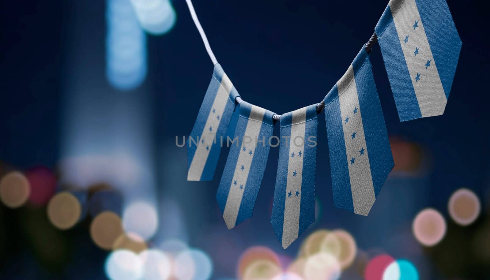 A garland of Honduras national flags on an abstract blurred background.