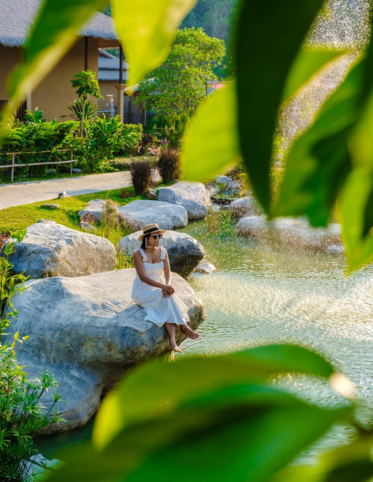 Asian women relaxing by a water pond in Khao Yai Thailand at sunset.