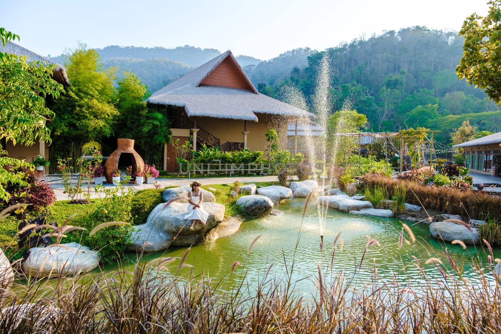 Asian women relaxing by a water pond in Khao Yai Thailand at sunset by fokkebok