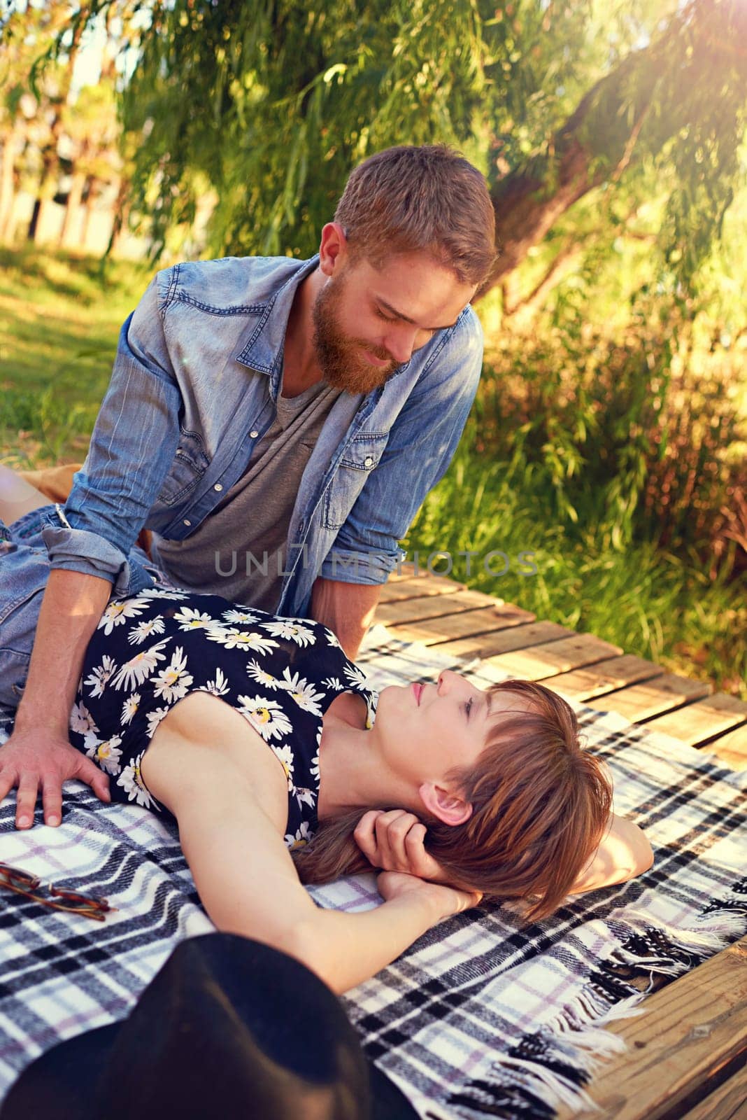 Park romance. an affectionate young couple lying on a blanket outdoors. by YuriArcurs