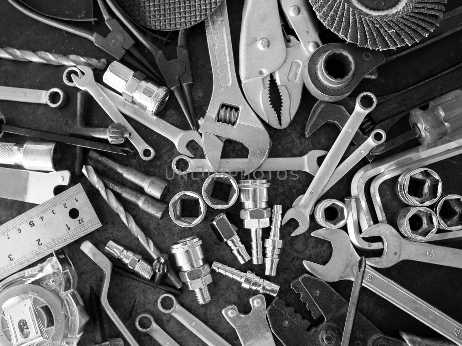 Hand tools consisting of wrenches, pliers, socket wrenches, laid out on old steel plate background.
