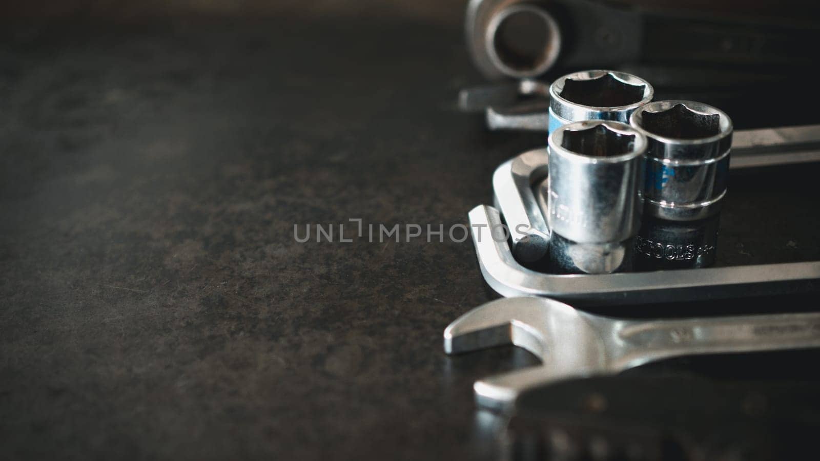 Hand tools consisting of wrenches, pliers, socket wrenches, laid out on old steel plate background.