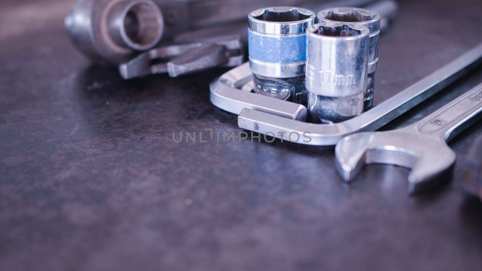 Hand tools consisting of wrenches, pliers, socket wrenches, laid out on old steel plate background.