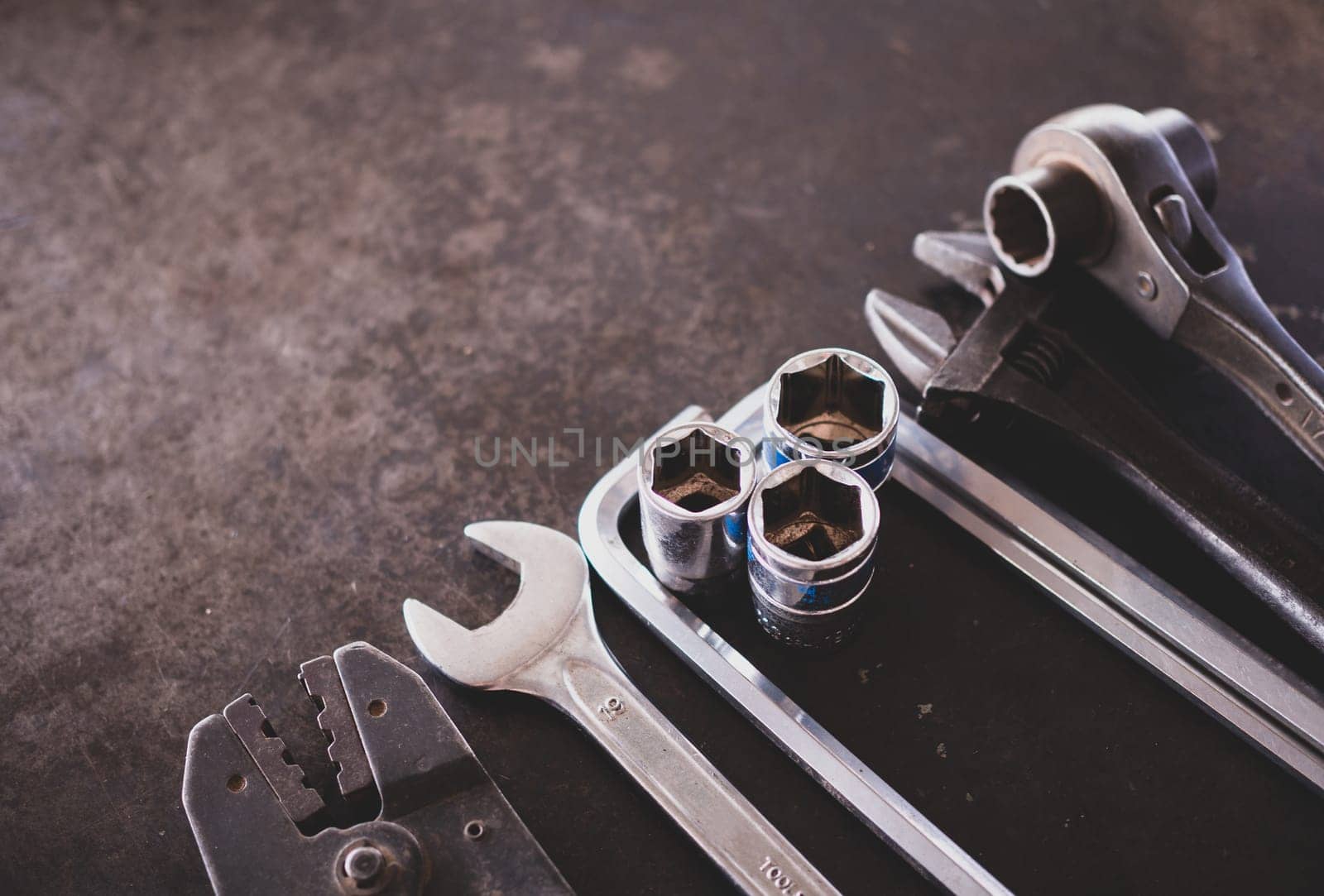 Hand tools consisting of wrenches, pliers, socket wrenches, laid out on old steel plate background.