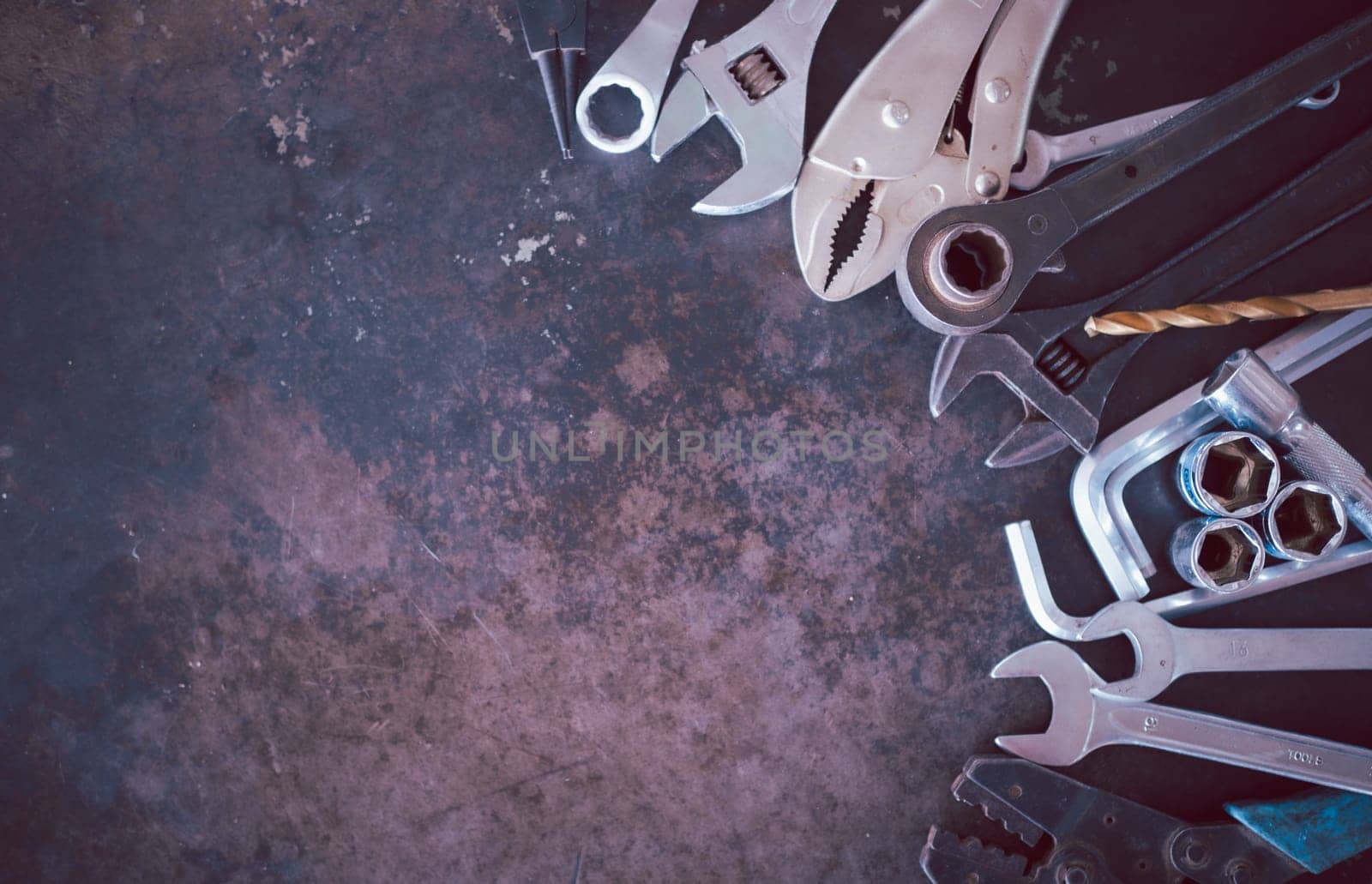 Hand tools consisting of wrenches, pliers, socket wrenches, laid out on old steel plate background.