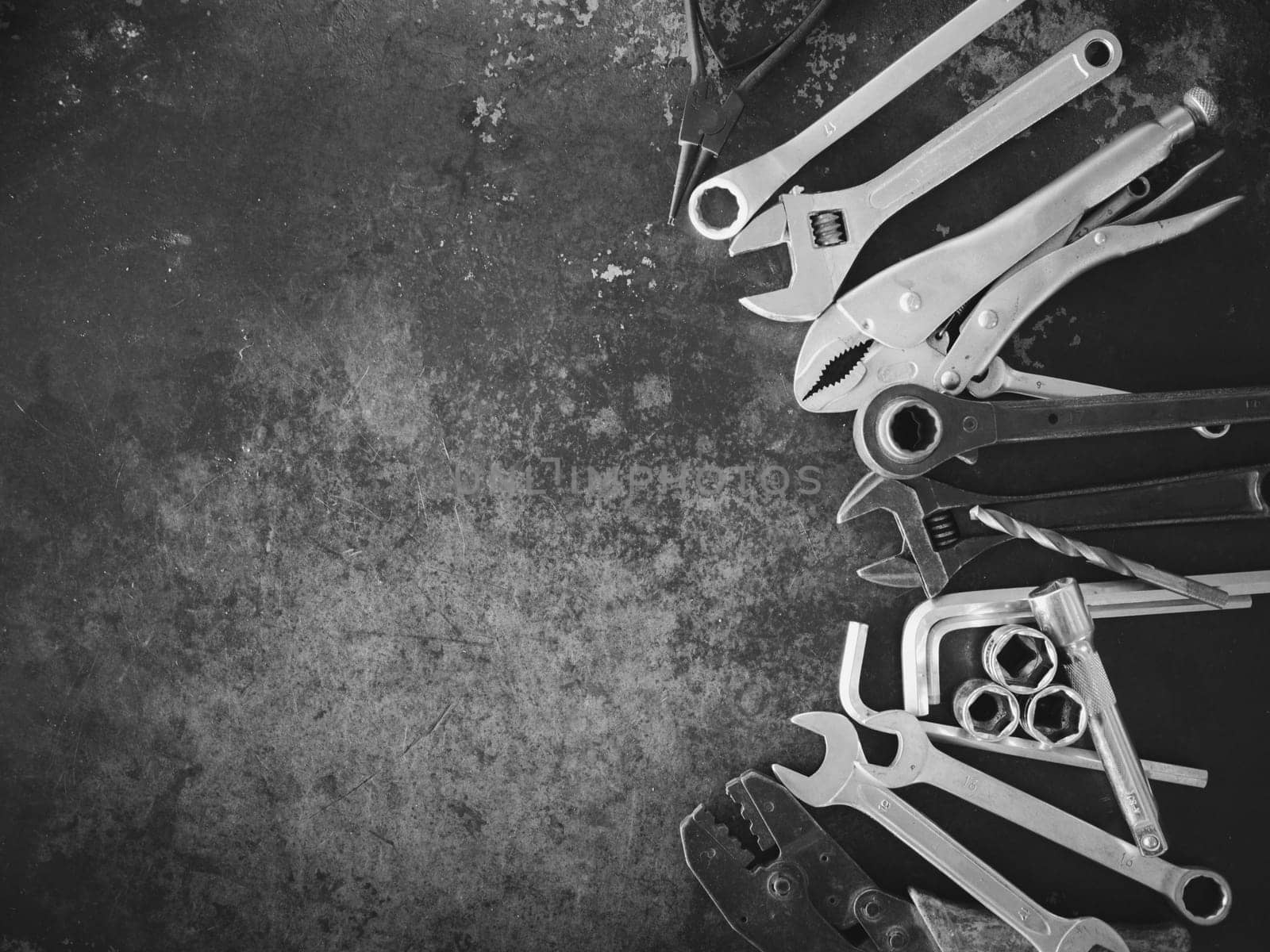 Hand tools consisting of wrenches, pliers, socket wrenches, laid out on old steel plate background.