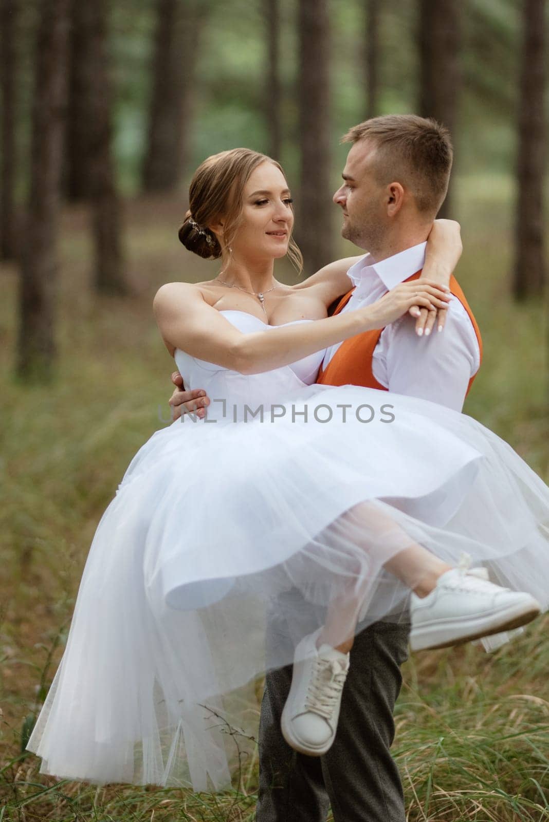 young couple bride in a white short dress and groom in a gray suit in a pine forest among the trees