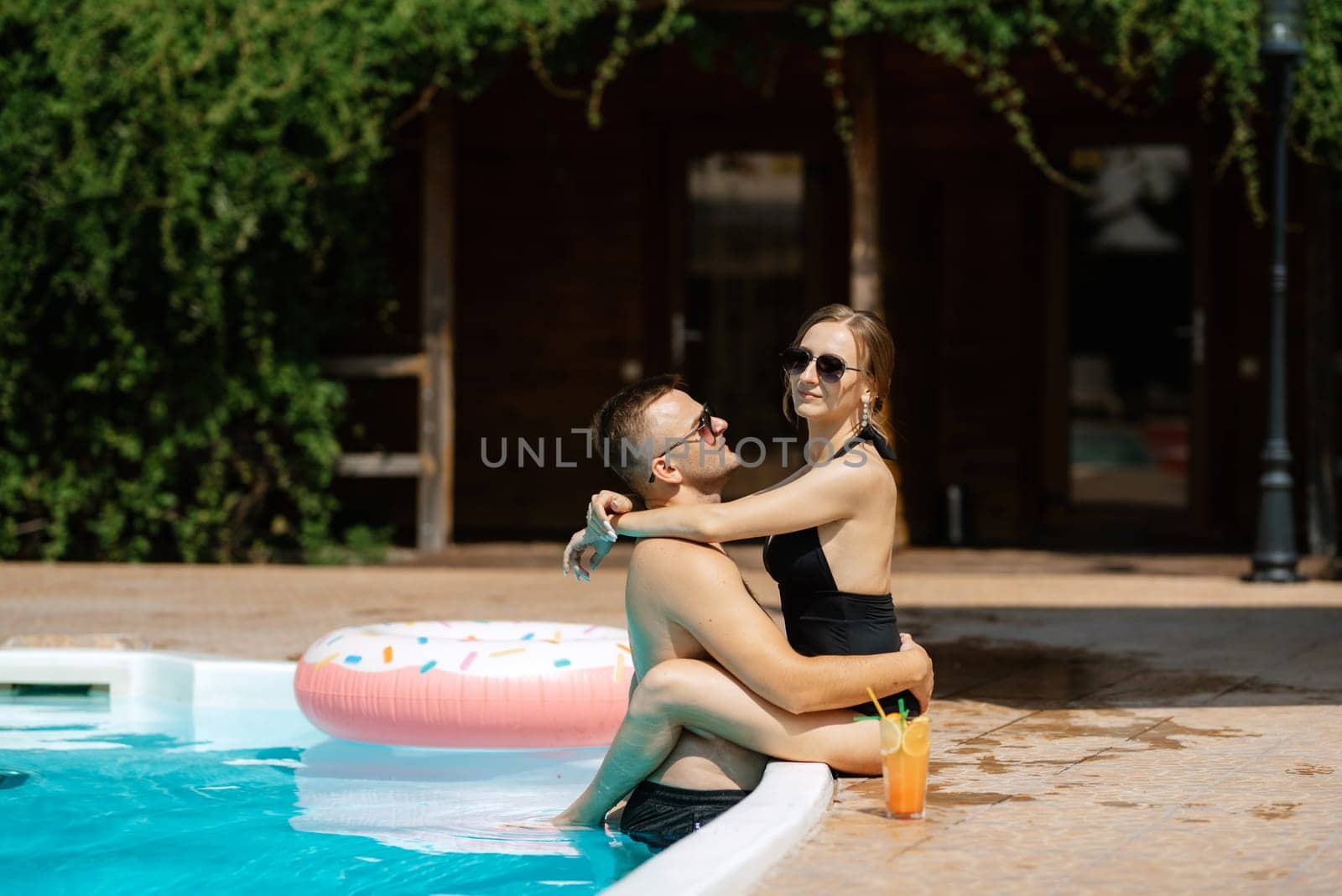 guy and a girl in bathing suits are relaxing, sunbathing and having fun near the blue pool