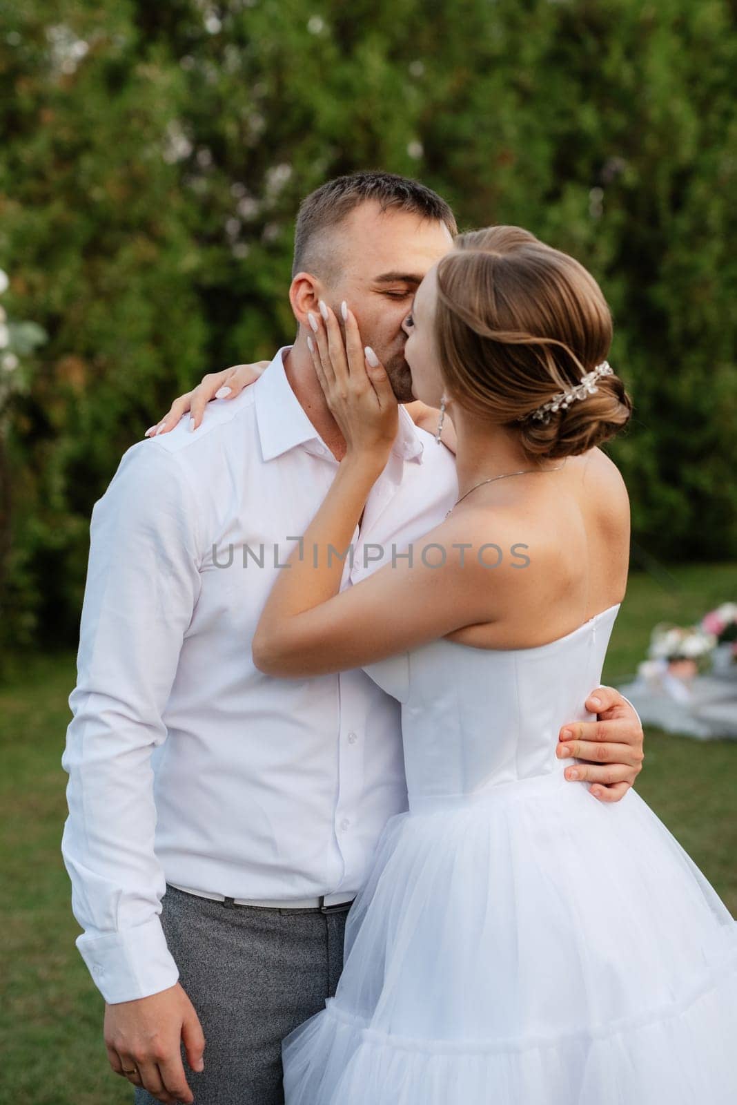 the first dance of the groom and bride in a short wedding dress on a green meadow