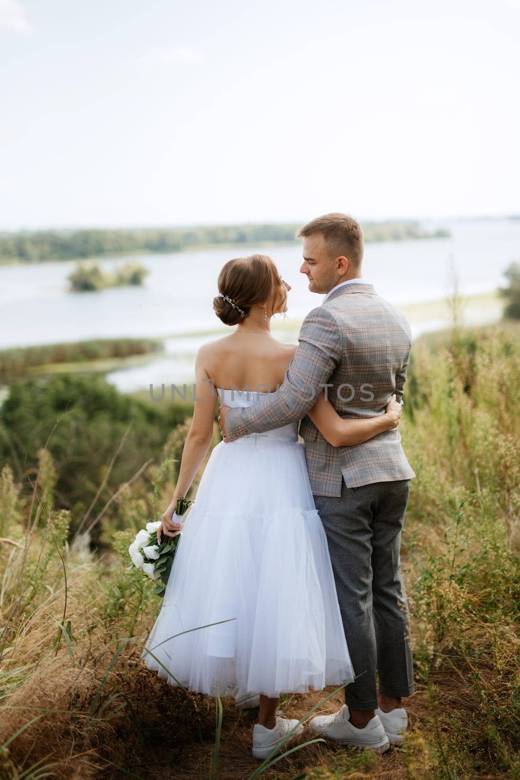 a young couple a guy and a girl are walking along the green hills near the river