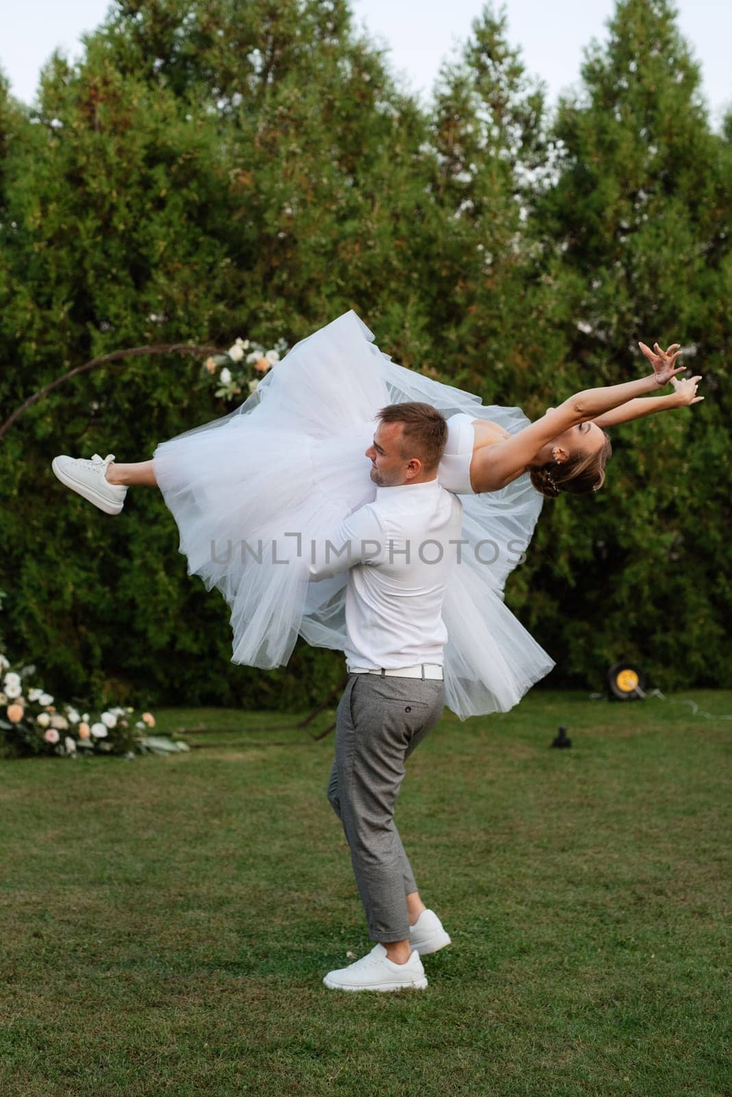 the first dance of the groom and bride in a short wedding dress on a green meadow by Andreua